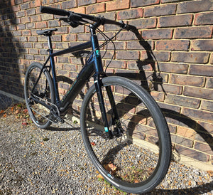 Black bicycle leaning against a brick wall