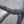 Close-up of a bicycle drop handlebar wrapped in black grip tape with small white reflective dots, photographed outdoors against a blurred gray background.