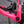 Close-up of a bright pink bicycle frame with a black SRAM brake mech in an outdoor setting.