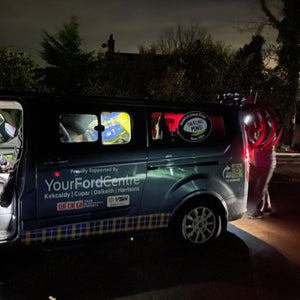 Van with multiple brand logos at night