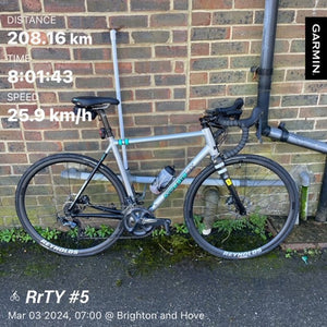Bicycle leaning against a brick wall with cycling statistics displayed, including brand 'Garmin'.