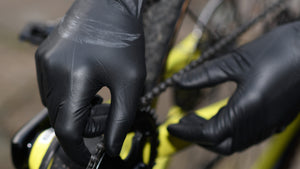 Person wearing black mamba gloves adjusting a bicycle chain 