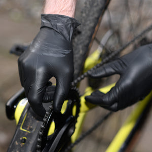 Person wearing black mamba gloves adjusting a bicycle chain 
