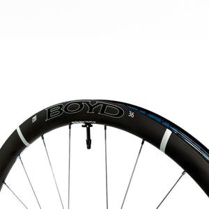 Close-up of a black Boyd Cycling 36mm carbon bicycle wheel rim with white decals and blue accents, shown against a solid white background.