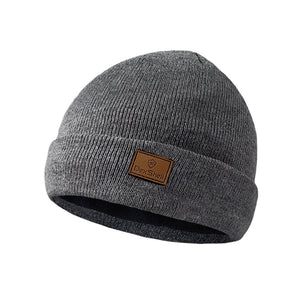A Dexshell Watch Beanie in Heather Grey on a white background with a folded cuff, featuring a brown rectangular leather patch on the front with the brand name 'DexShell'.