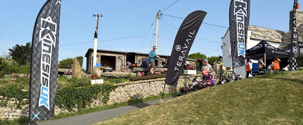 Dorset Gravel Dash Event with Trail banners and people in a grassy area.
