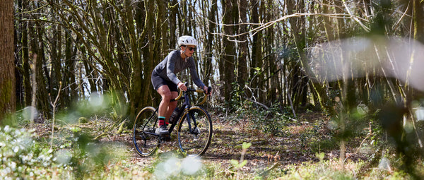 Close up of Fran riding a Kinesis Tripster AT through a wooded area.