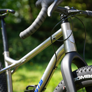Close-up of a Fernweh bicycle with 'KINESIS' head badge on a blurred green background