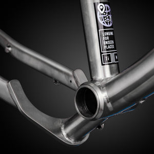 Close-up of a titanium bike frame with a label on a black background