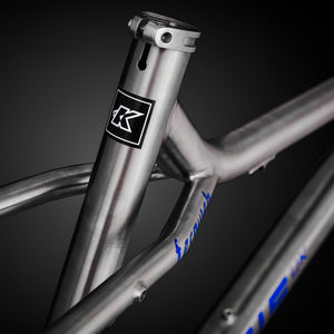 Close-up of a bicycle frame with a brand logo on a dark background