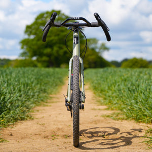 Kinesis Gravel Bicycle on a dirt path with greenery in the background front