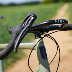 Close-up of bicycle handlebars with 'FARR' branding against a blurred natural background