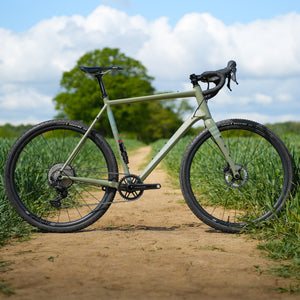 Kinesis Gravel Bicycle on a dirt path with greenery in the background, Kinesis Tripster Aluminium all terrain bike
