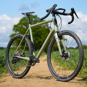 Kinesis Gravel Bicycle on a dirt path with greenery in the background, Kinesis Tripster Aluminium all terrain bike