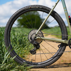 Close-up of a bicycle wheel with 'Challenge Gravine' tires on a natural background