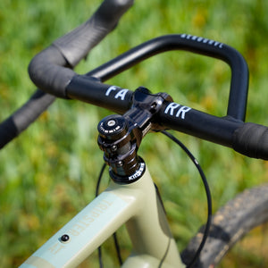 Close-up of bicycle handlebar with 'FARR' labels against a blurred green background