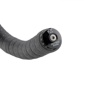 Close-up of a black bicycle handlebar grip tape end with a black end cap featuring the Kinesis brand logo and 'INSPIRING RIDING' text, on a white background.