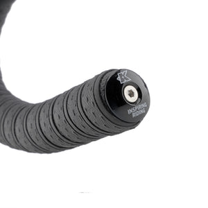 Close-up of a black bicycle handlebar grip end with a black metal cap featuring a silver bolt and the text 'INSPIRING RIDING' and a stylized 'K' logo, on a white background.