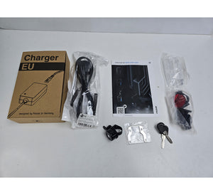 Charger kit with box, cable, key, and other accessories on a white surface