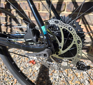 Close-up of a bicycle disc brake system with a brick wall background