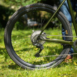 Close-up of a GX Race bicycle wheel with 'Hunt' branding on a grassy background