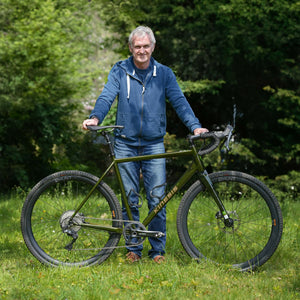 Scott standing next to his GX Race bike in a grassy area with trees in the background
