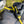 Close-up of a black and yellow bungee accessory with a black plastic clip or toggle, attached to a dark fabric bag outdoors.