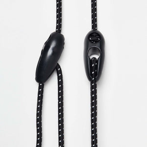 Black and white adjustable Wholegrain Cycles bungees with stitching and two black plastic toggle sliders, shown on a clean white background.
