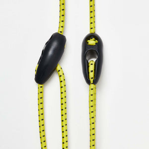 Wholegrain Cycles bungees in Bright yellow with black dotted pattern and black plastic toggle hardware, shown on a clean white background.
