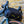 A black Wholegrain Cycles bicycle pannier bag with yellow accents strapped to a bicycle's frame, leaning against a yellow brick wall.