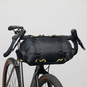 A Wholegrain Cycles Carrie rack and bag mounted to a gravel bike's handlebars and secured with straps and yellow bungees.