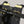Close-up of a black bicycle handlebar bag with bright yellow accents and loops, mounted over black handlebars. The brand name 'Carrie' is visible on a small black label.