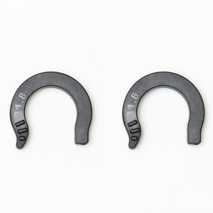 Two dark gray horseshoe-shaped plastic spacers with white measurement markings, 31.8mm displayed side by side on a plain white background.