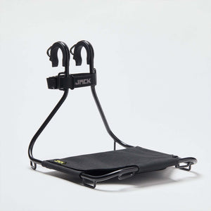A black Wholegrain Cycle Jack bicycle rack with a padded support and two upright mounting arms, shown on a clean light gray studio background. The brand name 'JACK' is visible on the strap and small yellow logo on the seat.