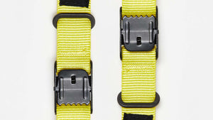 Two Wholegrain Cycles Stiff Straps with black plastic buckles and black fabric tabs printed with a stylized green logo, shown on a plain white background.
